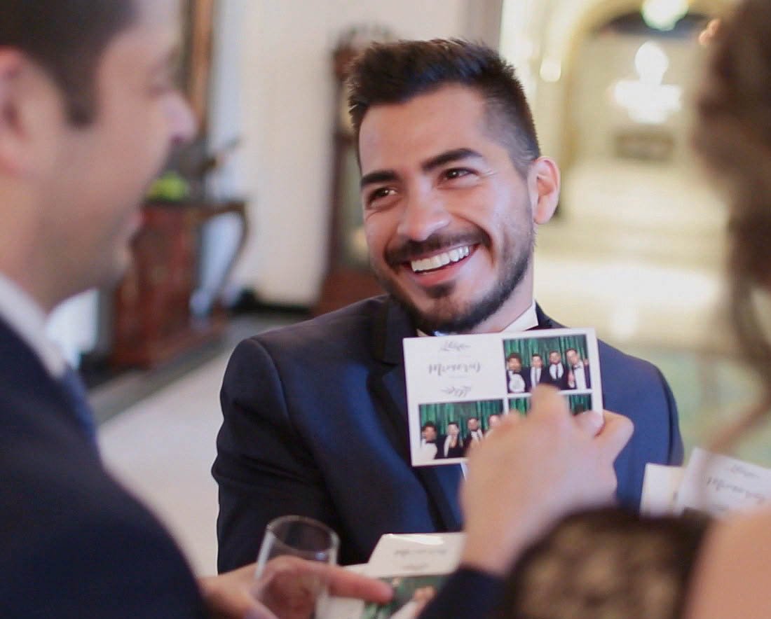 Guest smiling while holding his photobooth print strip