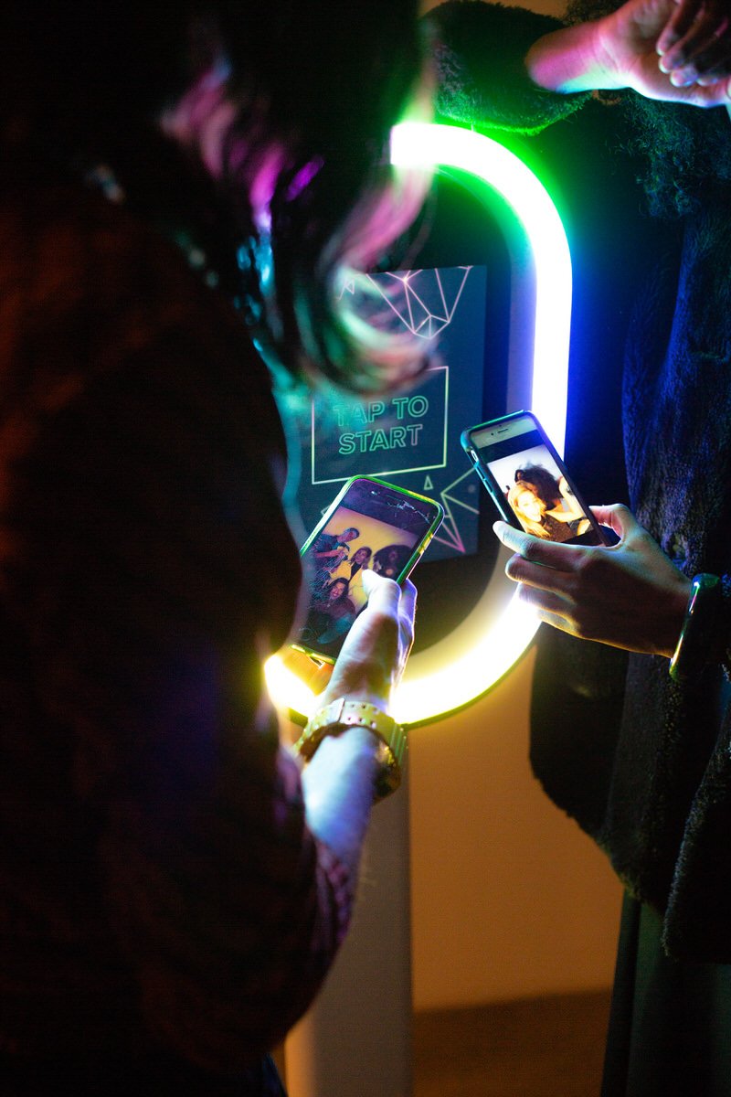 Guests viewing their photos on their phones next to the modern digital photobooth
