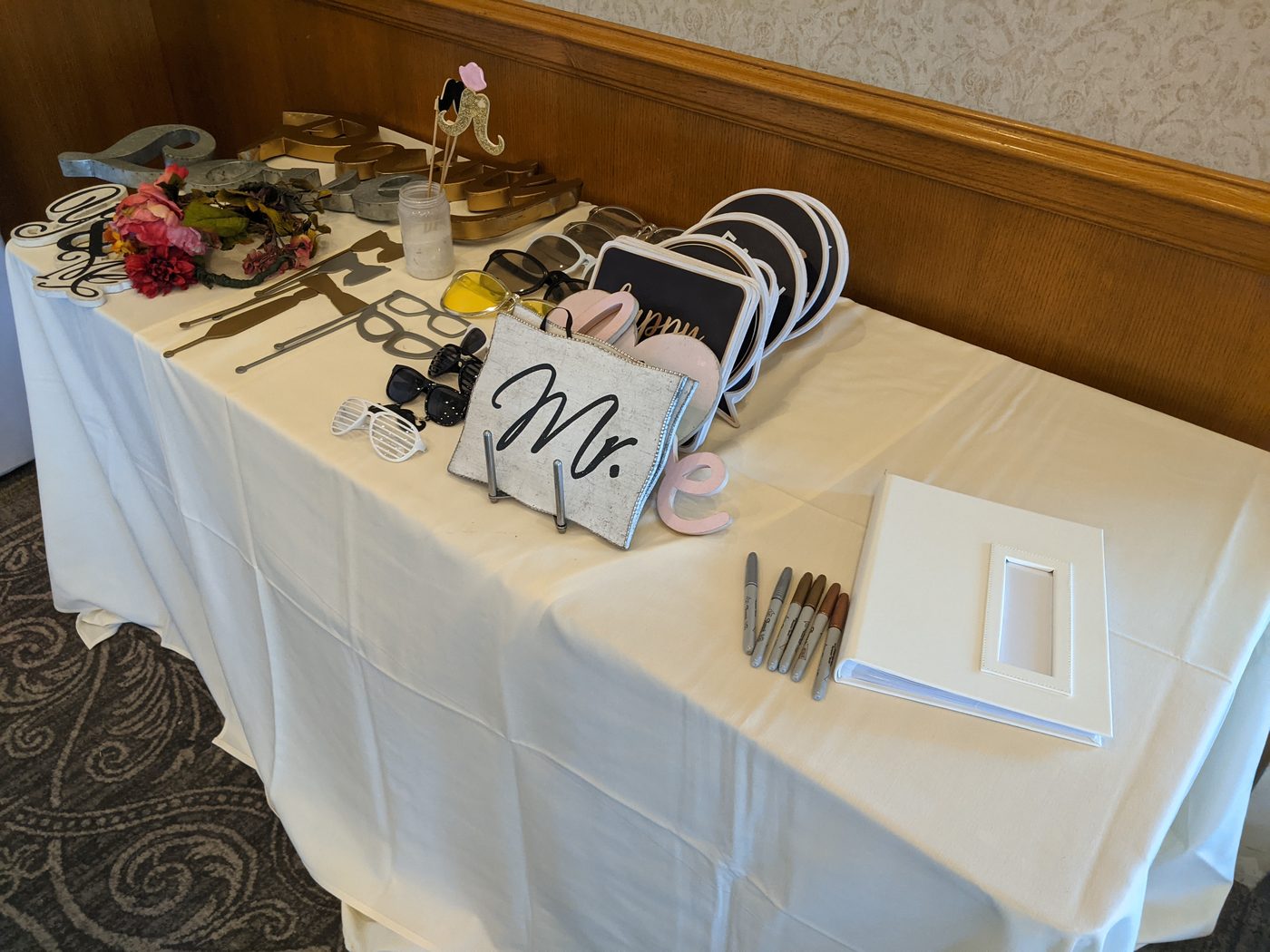 Photobooth prop table with florals and wedding sign props in a hotel ballroom