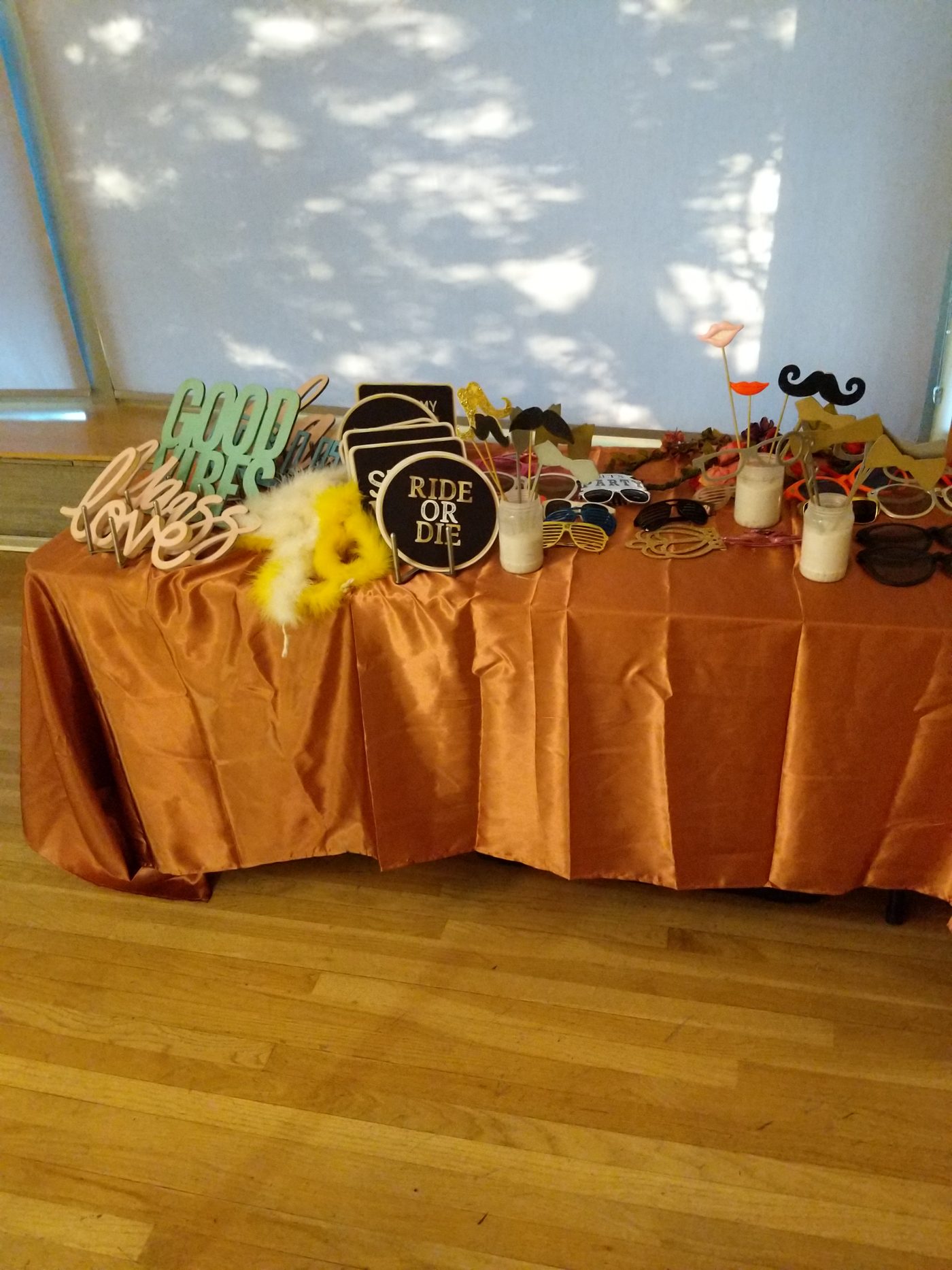 Photobooth prop table with a 'Bride or Die' sign and feather boa at a reception
