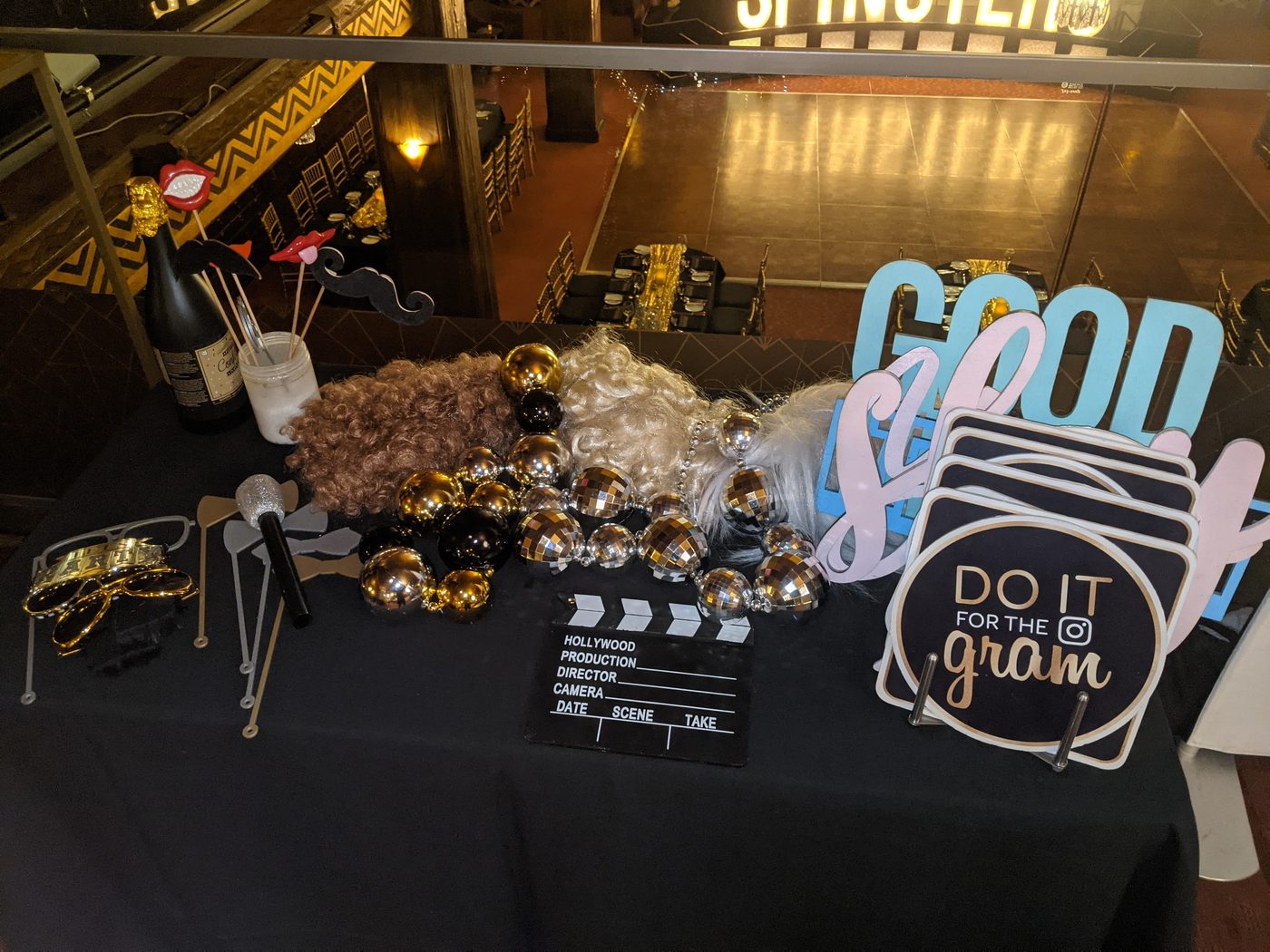 Photobooth prop table with a 'Do It For The Gram' clapperboard sign and gold decor